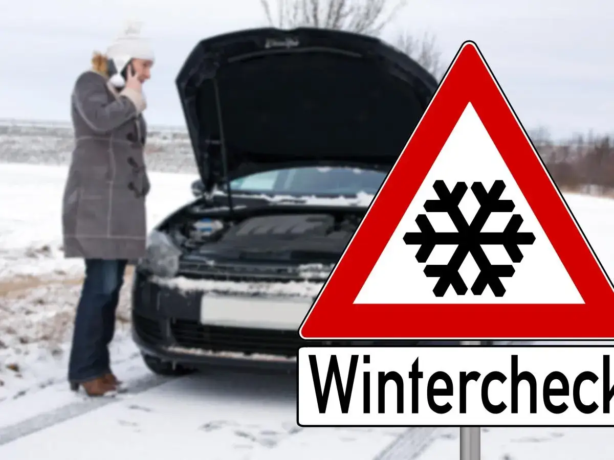Frau mit offenem Kofferraum im Schnee telefoniert. Warnschild mit Schneeflocke und Aufschrift
