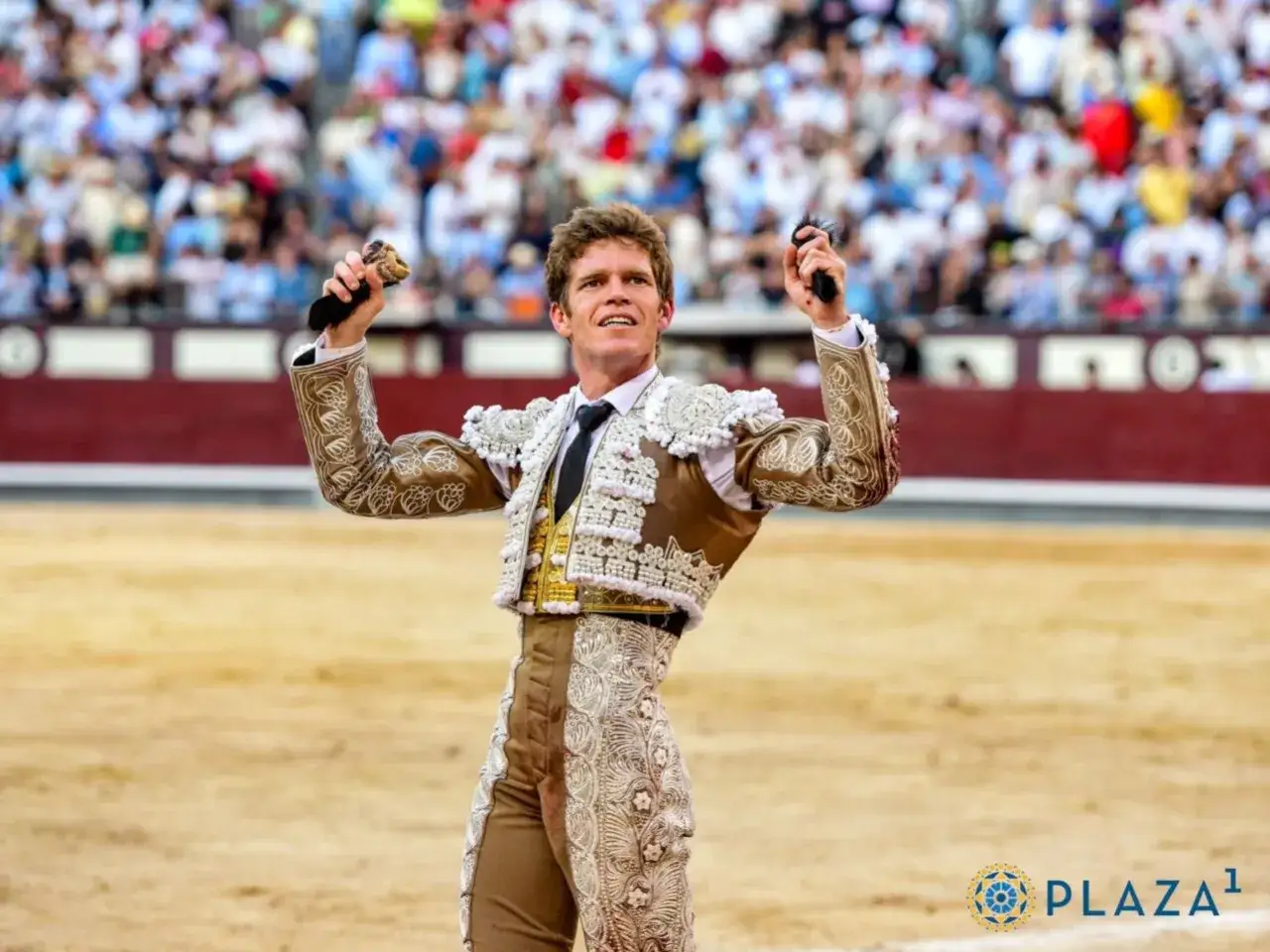 Borja Jim&eacute;nez torero, con traje de luces bordado, levanta los brazos en la arena ante una multitud.