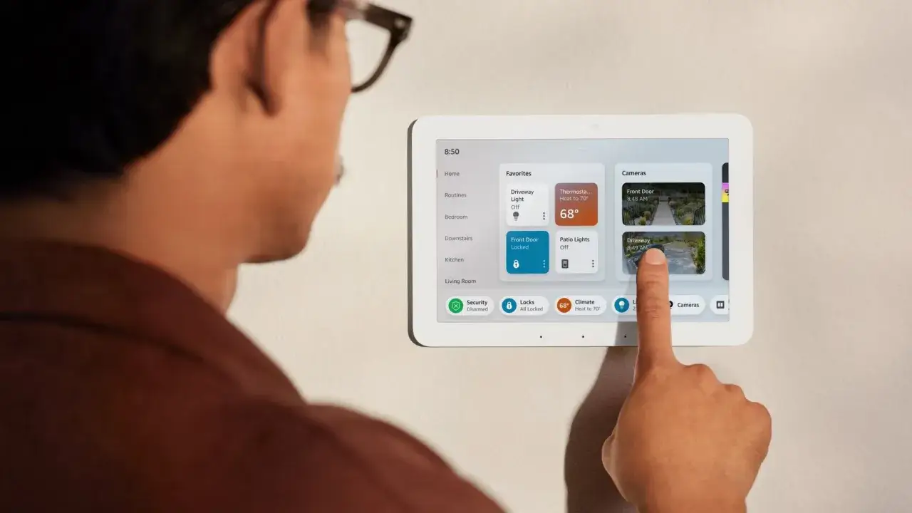 Ein Mann interagiert mit einem Smart-Home-Display, das zeigt, was Alexa steuern kann: Lichter, Thermostat und Kameras.