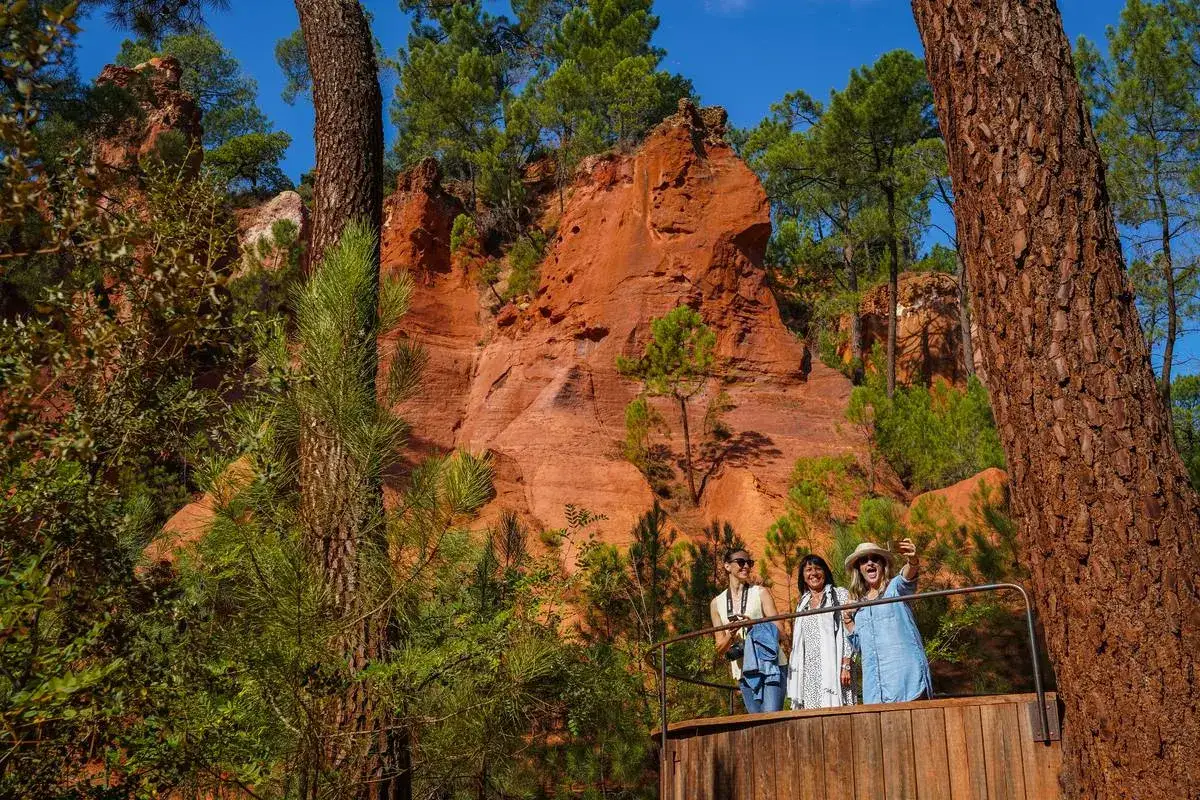 Trois femmes profitent d'une randonn&eacute;e dans le Luberon, admirant les falaises ocres et la for&ecirc;t verdoyante.