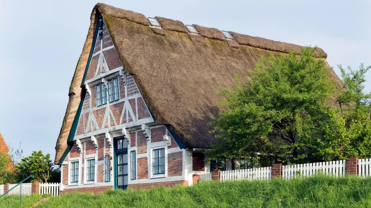 Ein reetgedecktes Haus mit Fachwerkelementen. Die Frage 