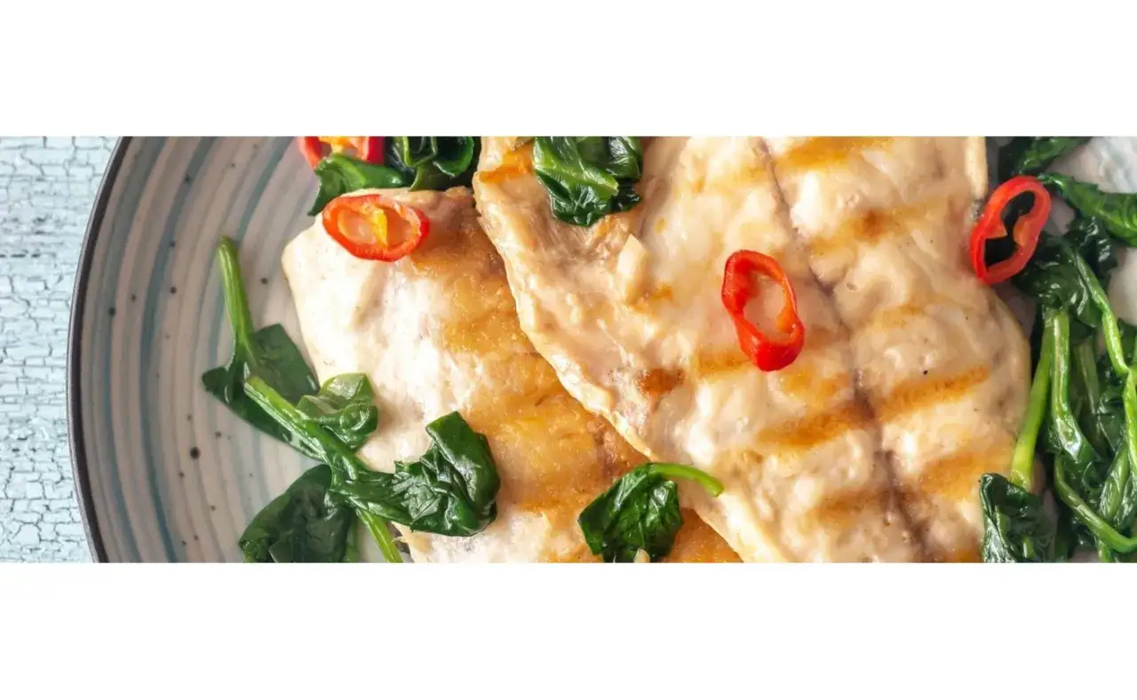 Dorada a la plancha con espinacas y rodajas de chile rojo.