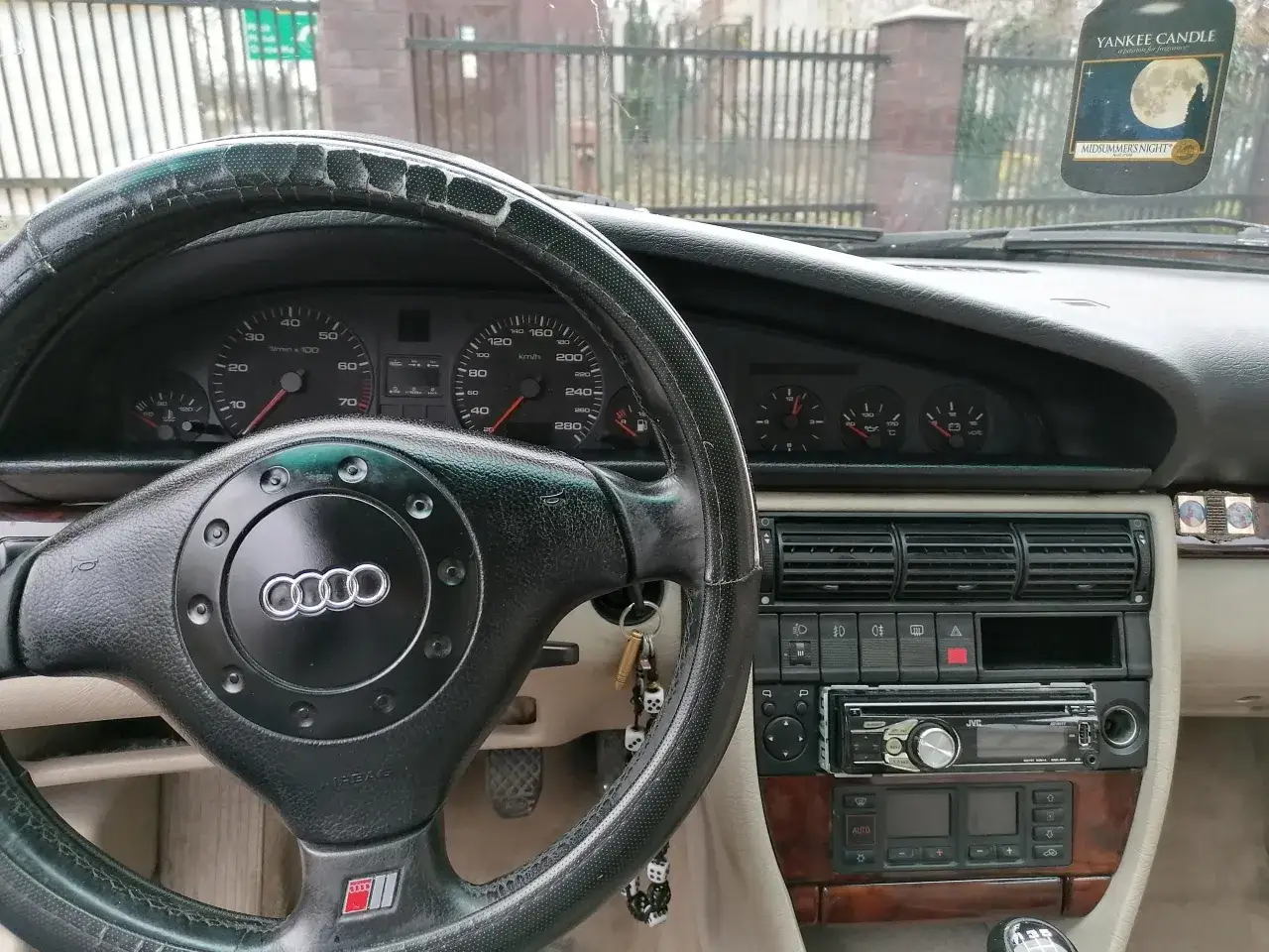 Wnętrze Audi A6 C4 z kierownicą, deską rozdzielczą i radiem JVC. Na kierownicy widać logo Audi.