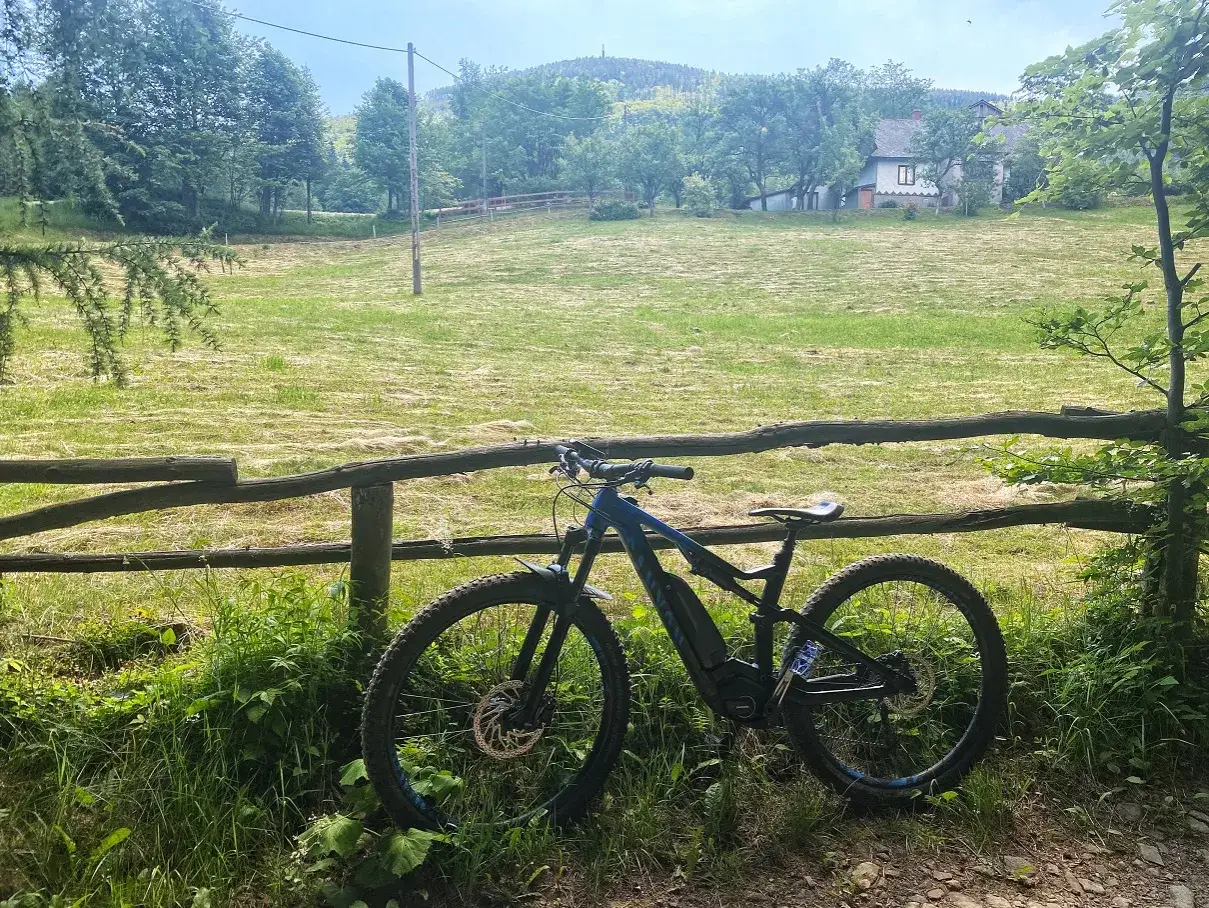 Rower elektryczny czeka na podjeździe na Skrzyczne. Piękny widok na Beskidy i sielską chatkę.