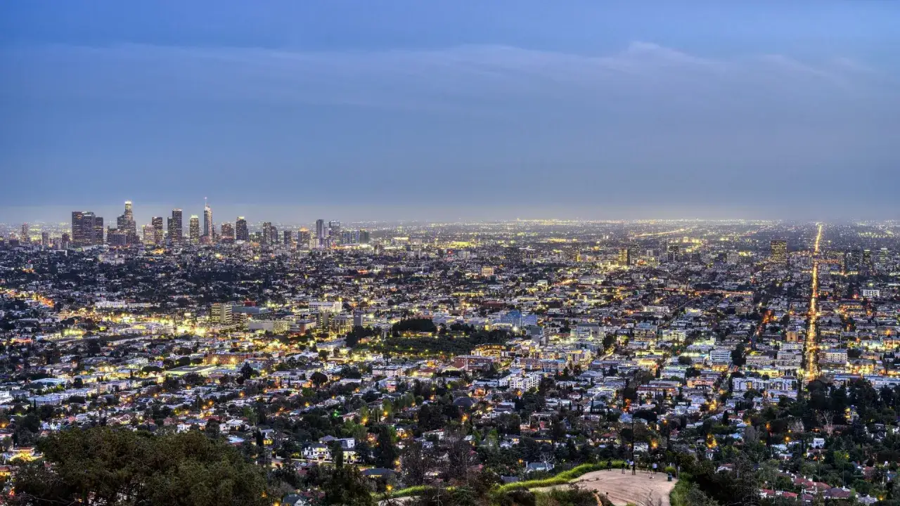 Vista panoramica di Los Angeles illuminata di notte. Un'infinità di luci urbane si estende all'orizzonte, con grattacieli che svettano. Perfetto per chi cerca dove dormire a Los Angeles.