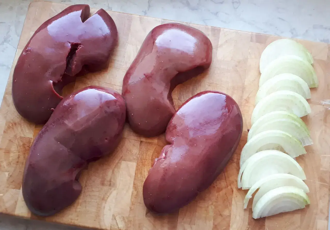 Cynaderki co to? Oto surowe, ciemnoczerwone cynaderki i pokrojona w krążki cebula na desce.