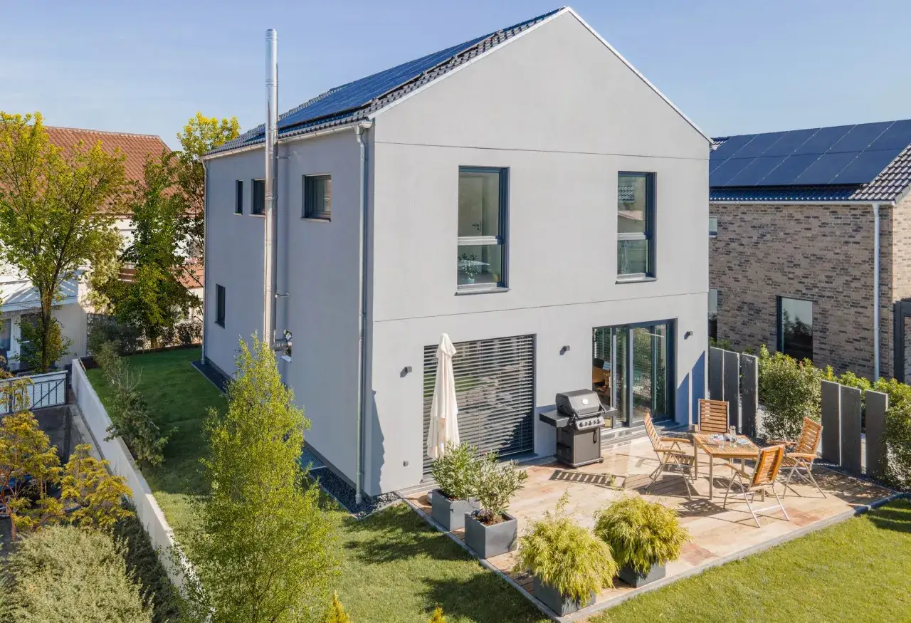 Ein schmales Haus mit Solaranlage auf dem Dach und einem Grill auf der Terrasse.