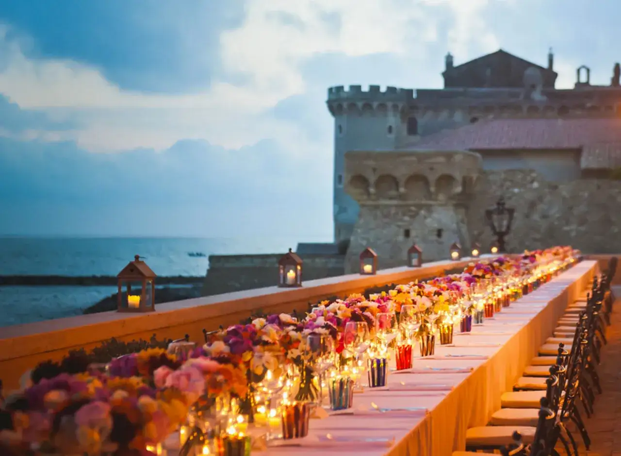 Tavola imbandita per un matrimonio in spiaggia, con fiori colorati e lanterne. Un'idea per un matrimonio in spiaggia come vestirsi uomo.