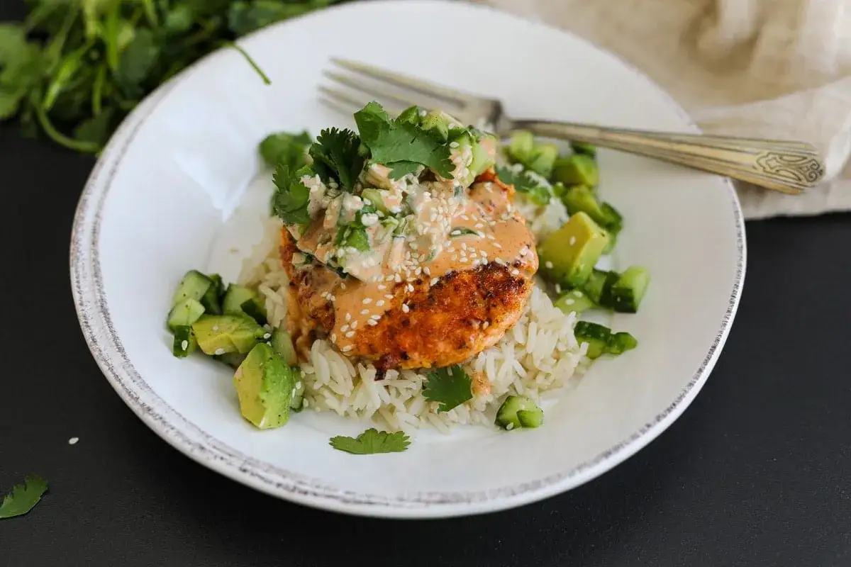 Saftiger pulled Lachs auf Reis, garniert mit Avocado, Gurke und Koriander. Ein köstliches Gericht, das Lust auf mehr macht.