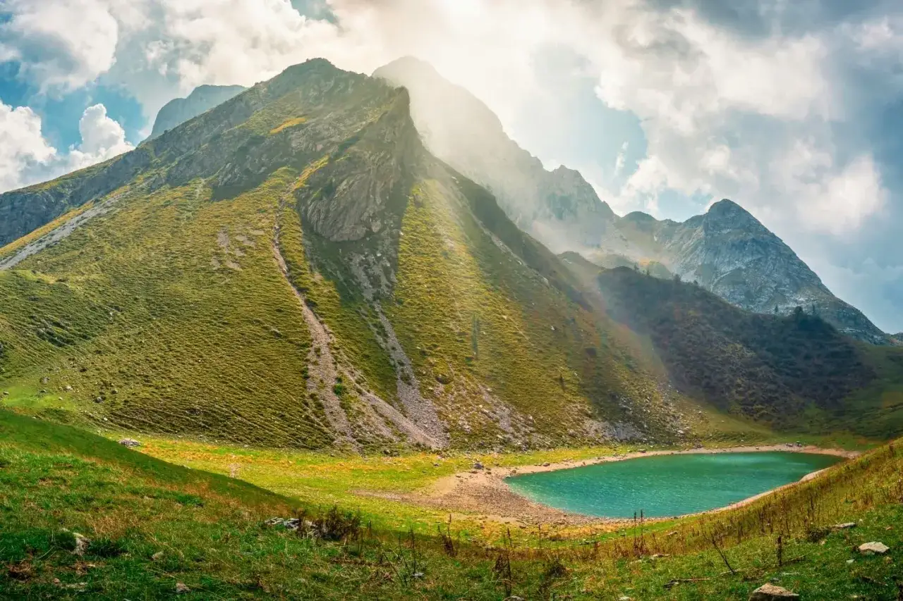 Un lago alpino turchese ai piedi di montagne verdi, ideale per il trekking vicino Milano.
