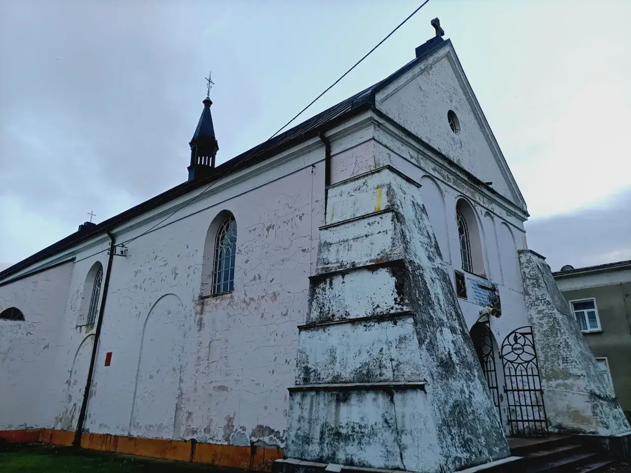 Stara, jasnoróżowa świątynia w **Szczuczynie** z charakterystyczną wieżyczką i ozdobną bramą.