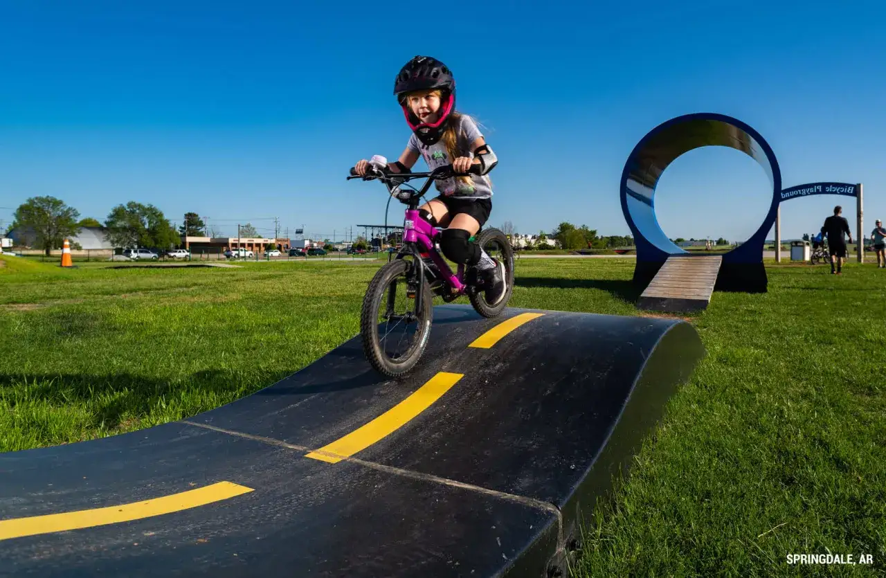 Dziewczynka na rowerze dla 9 latka pokonuje przeszkody na pumptracku.