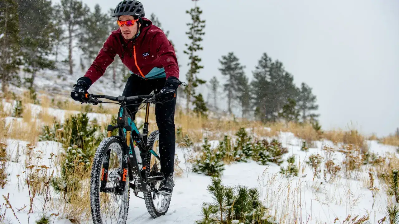 A man mountain biking in the winter snow, proving you can indeed ride in the cold.
