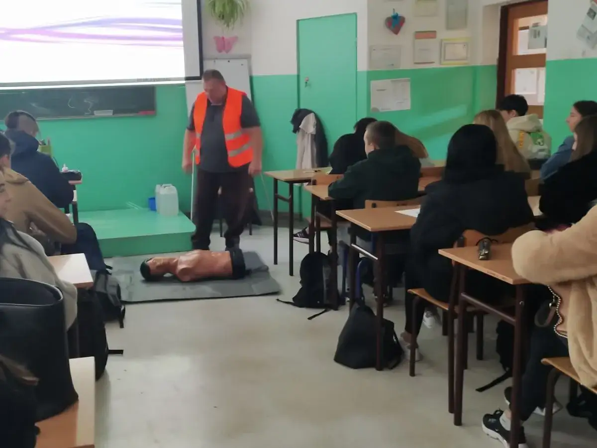 Szkolenie z pierwszej pomocy, manekin do resuscytacji i uczniowie. To ważny element promocji zdrowia.
