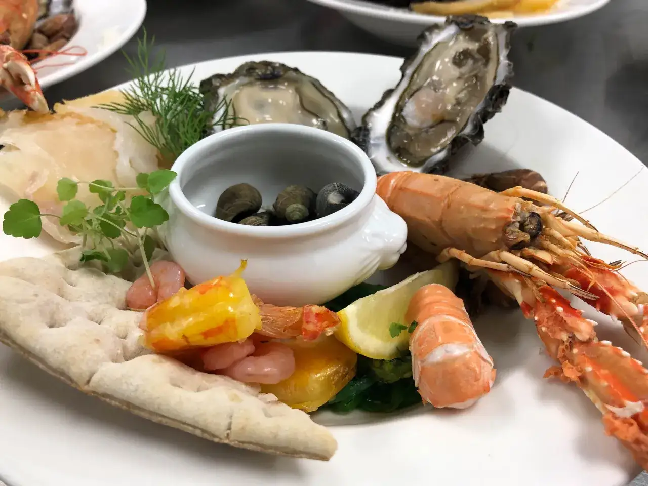 Une assiette de fruits de mer pour une personne : huîtres, crevettes, langoustines, coquillages et pain.