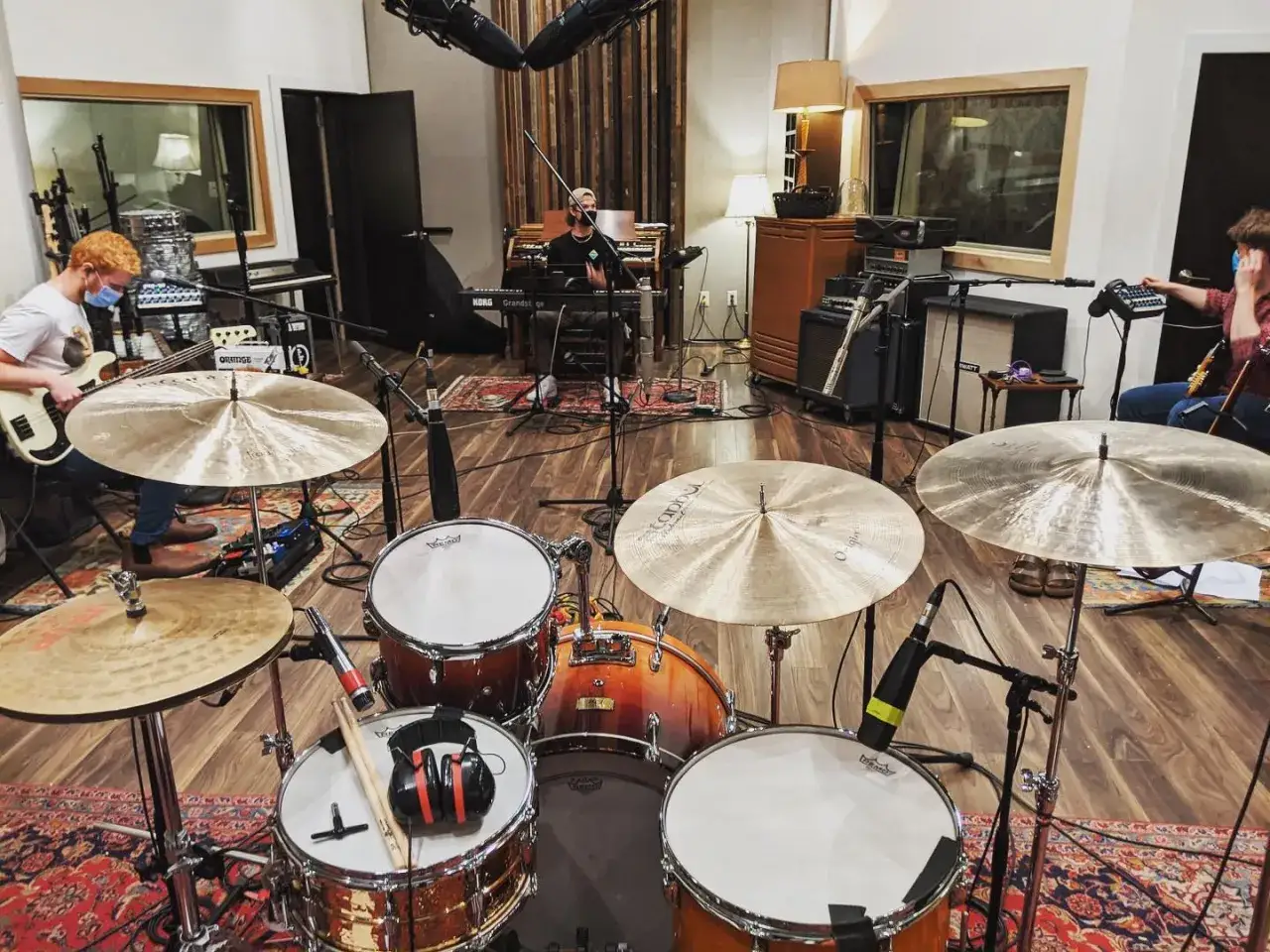 Band bei einer **live recording** im Studio. Ein Bassist, ein Keyboarder und ein Schlagzeuger sind zu sehen.