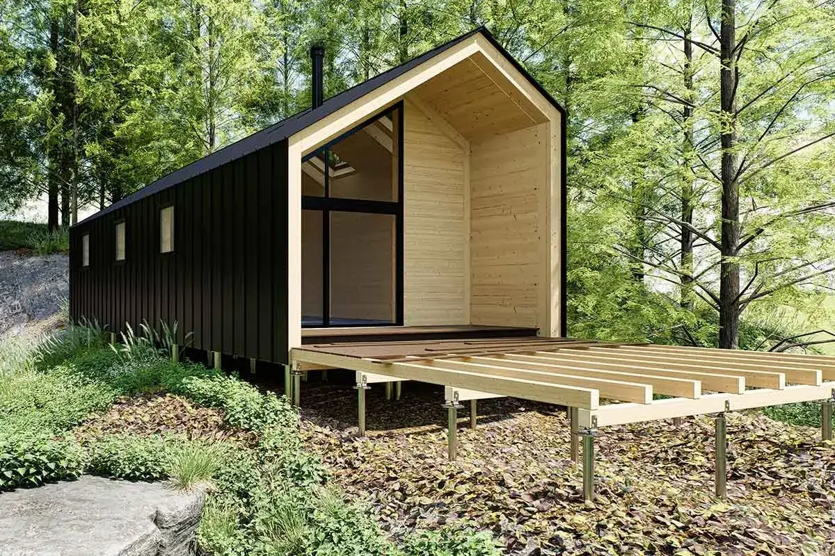 Modernes Holzhaus im Wald, dessen **Terrasse renovieren** wird. Die Holzkonstruktion steht auf Stelzen, umgeben von üppiger Vegetation.