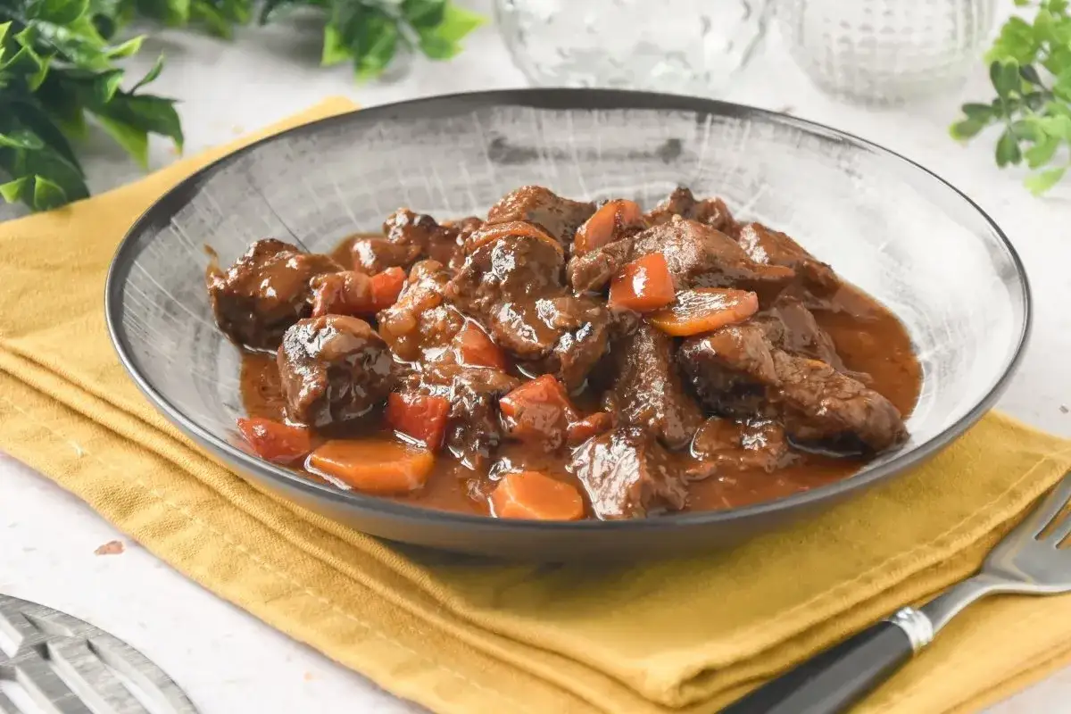 Un plato humeante de carne al toro, tiernos trozos de carne estofada con zanahorias en una rica salsa.