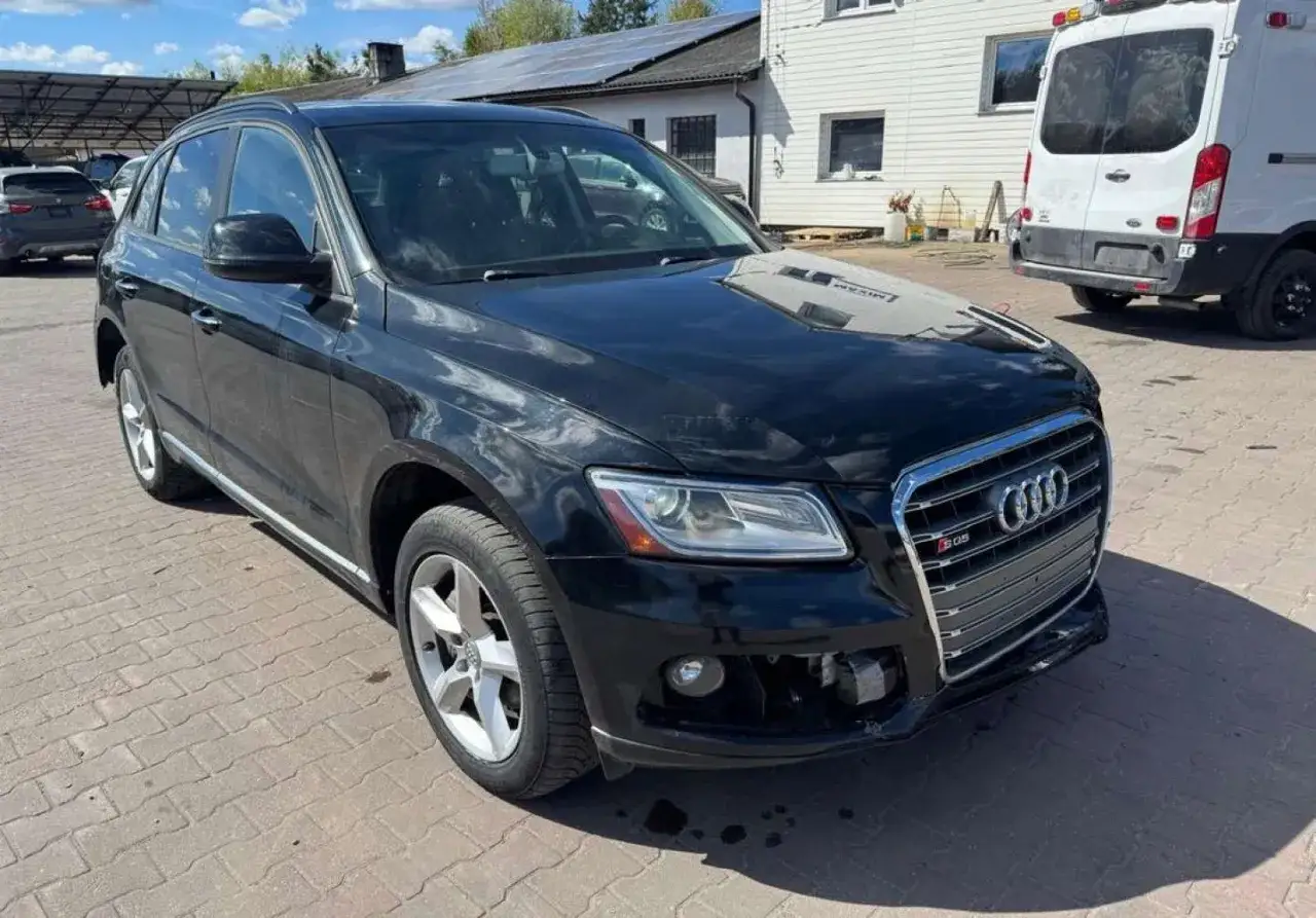 Czarny Audi Q5 8R z chromowanym grillem i oznaczeniem S-line, zaparkowany na kostce brukowej.
