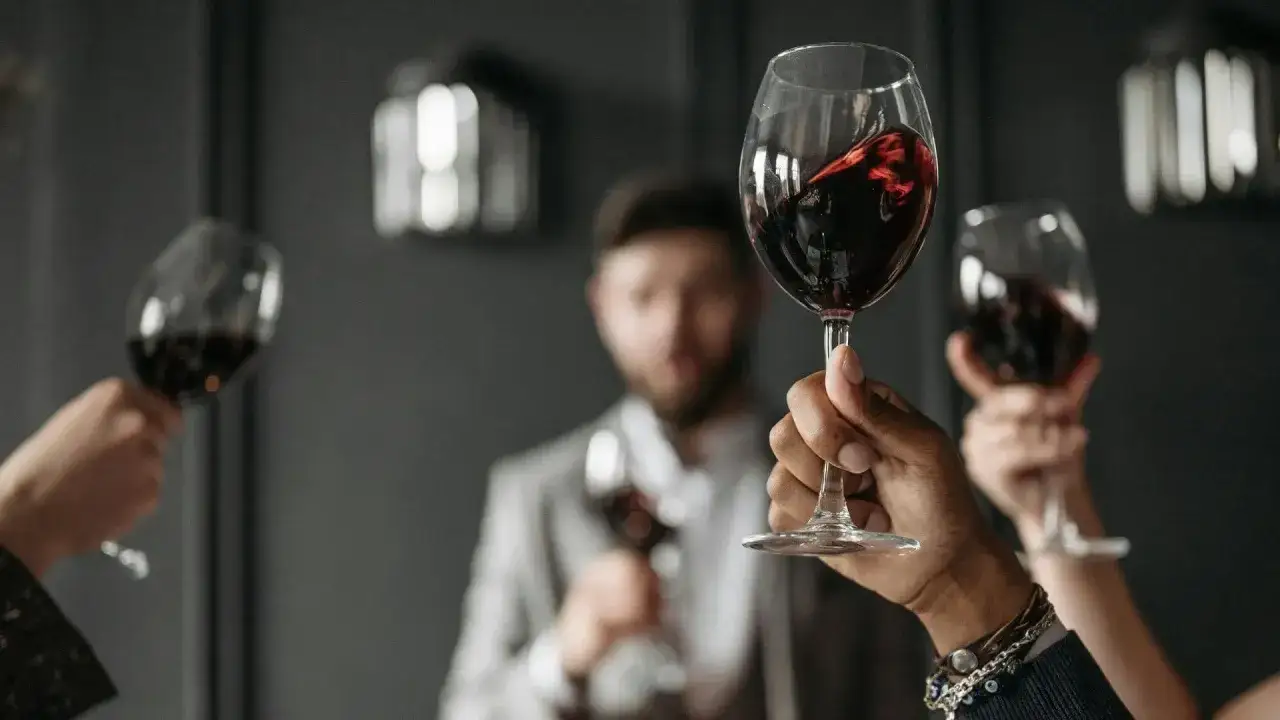 Ludzie wznoszą kieliszki z czerwonym winem, celebrując degustacje wina.