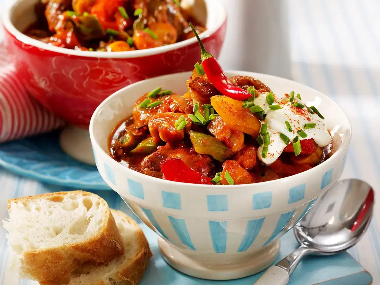 Herzhaftes Schweinegulasch mit Paprika, garniert mit Sauerrahm und Chili. Ein tolles Schweinegulasch Rezept für gemütliche Abende.