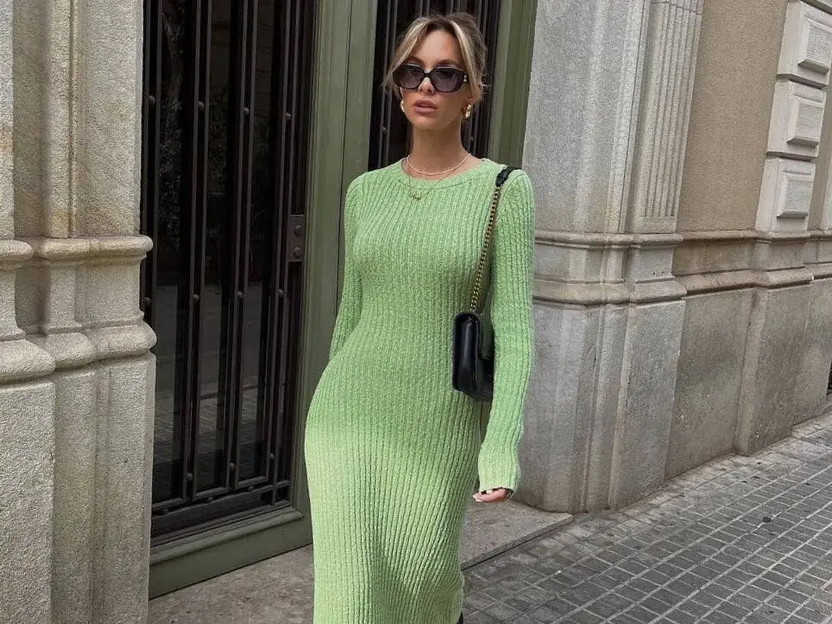 Mujer con vestido de punto de **color verde claro**, bolso negro y gafas de sol, posando en la calle.