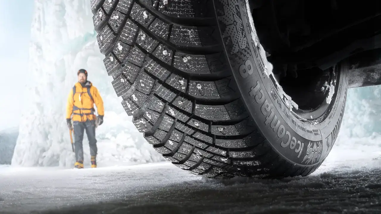 En man i gul jacka står vid en isvägg. Ett Continental IceContact 3-däck med dubb visar sin greppförmåga på isen.