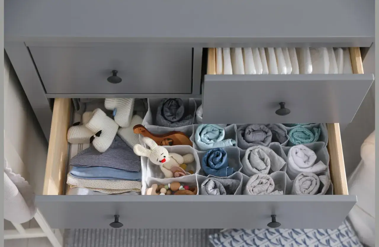Ordentliche Schubladen einer Wickelkommode: Windeln oben, Babykleidung und Spielzeug unten, übersichtlich sortiert.