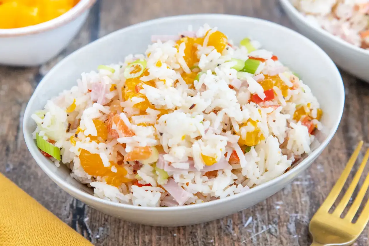 Omas Reissalat: Ein bunter Reissalat mit Orangenst&uuml;cken, Schinkenw&uuml;rfeln und Fr&uuml;hlingszwiebeln in einer Sch&uuml;ssel.