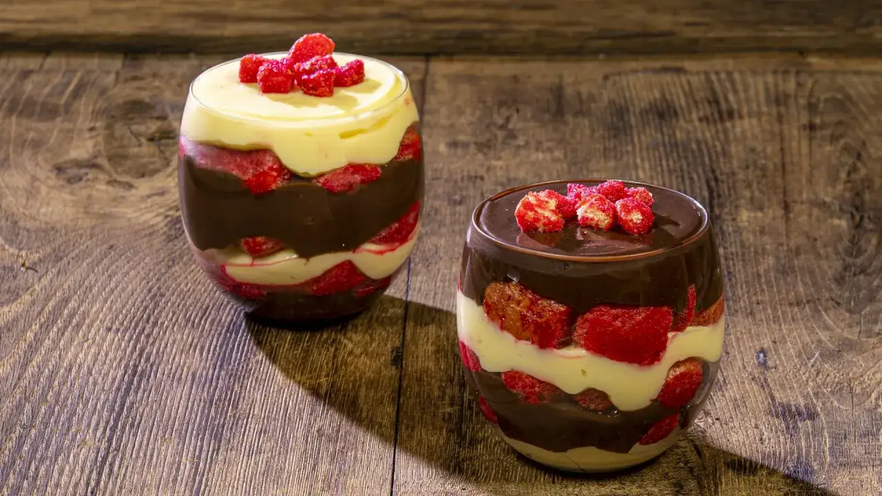 Due bicchieri di zuppa inglese tradizionale, con strati di crema pasticcera, cioccolato e fragole, guarniti con fragoline.