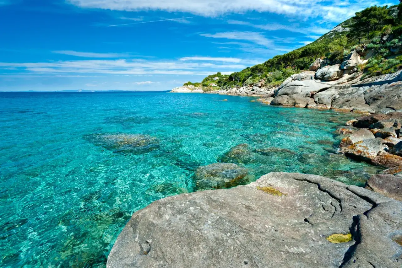 Mare cristallino e scogli su una costa verdeggiante all'Isola d'Elba.