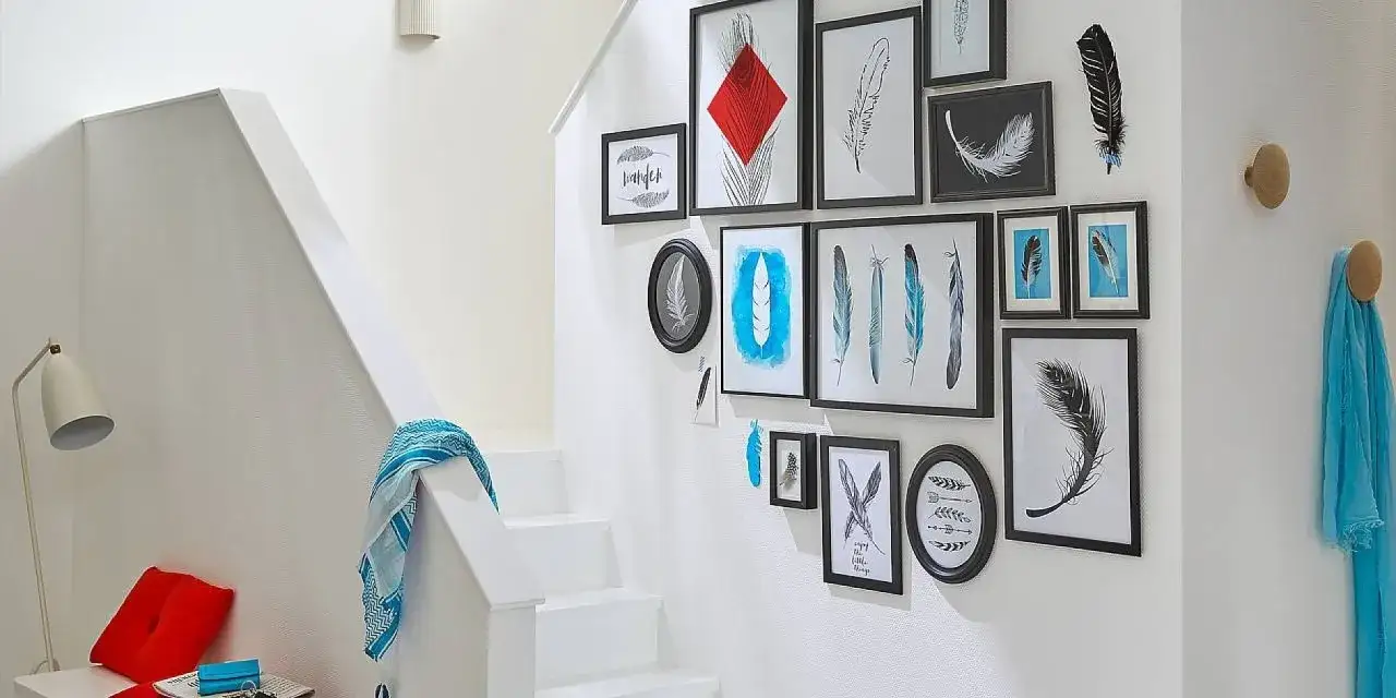Galeria piór na ścianie przy schodach. Zobacz, jak powiesić obraz, by stworzyć efektowną aranżację.