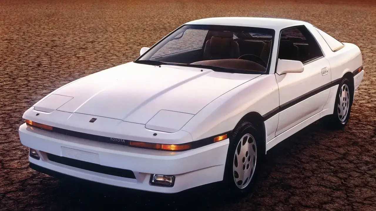 Biała Toyota Supra z lat 80. na pustynnym tle. Ikona motoryzacji, która zapisała się w historii.