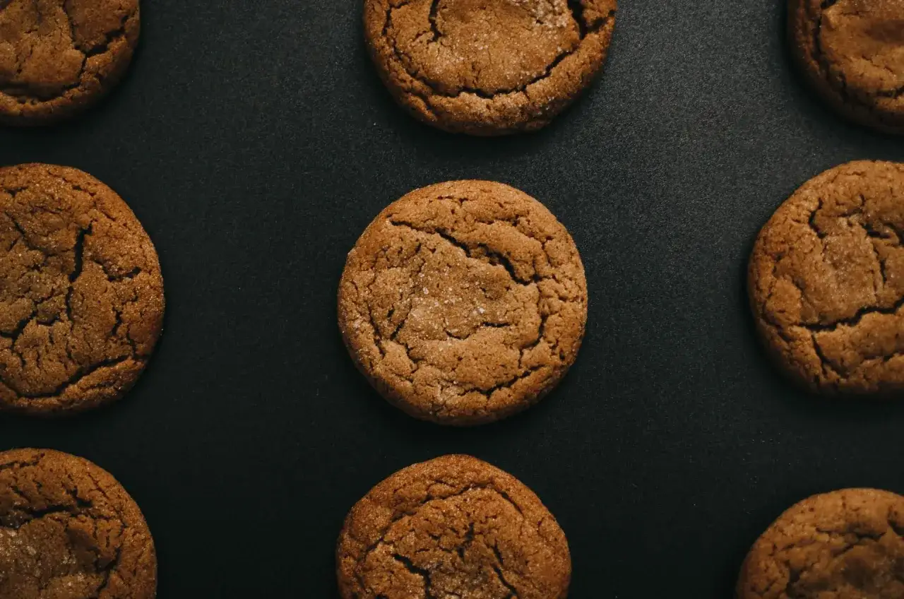 Galletas caseras con az&uacute;car espolvoreada, dispuestas sobre una superficie oscura.