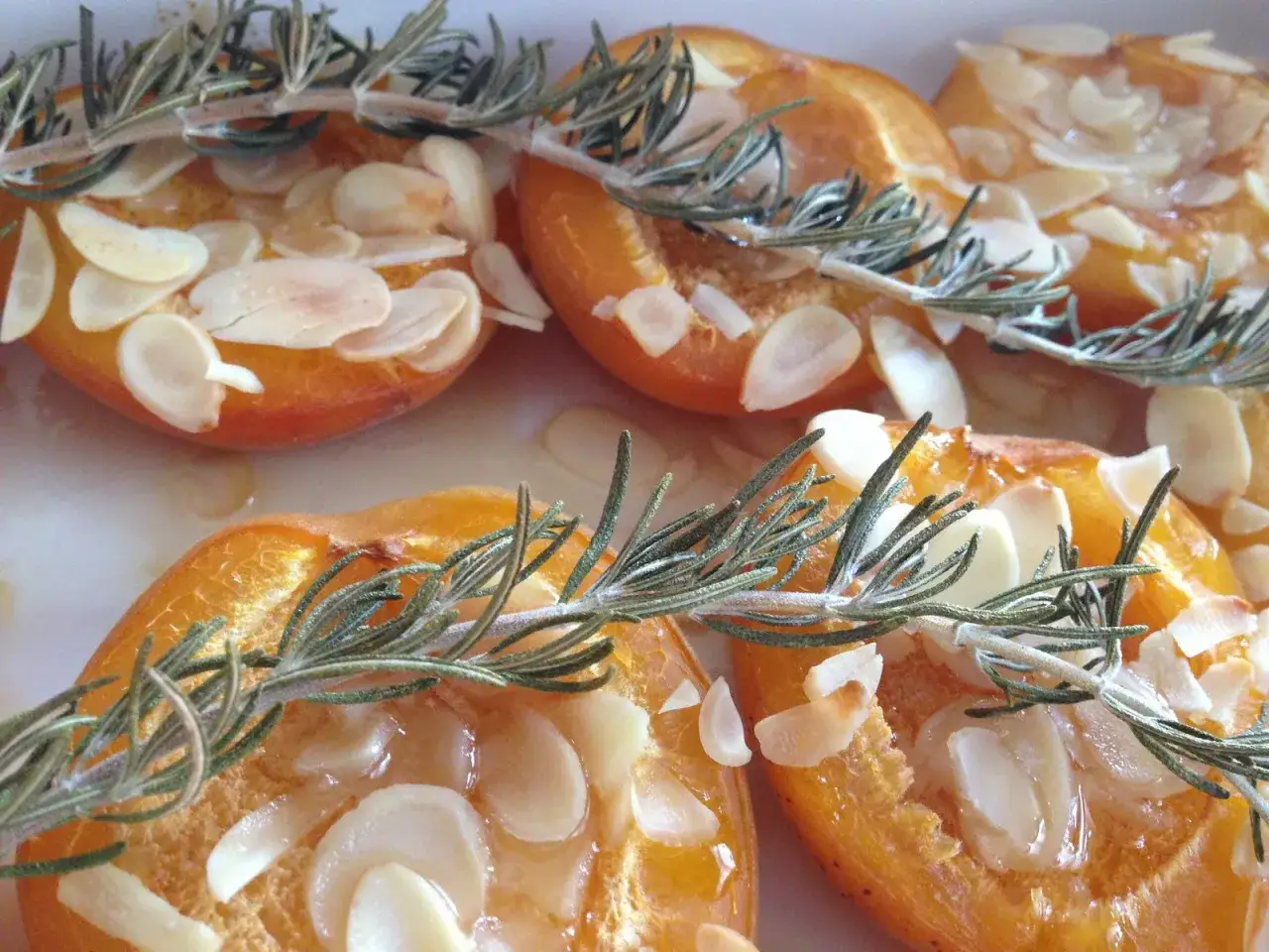 Abricots rôtis au four, garnis d'amandes effilées et d'une touche de romarin frais. Un délice sucré et parfumé.