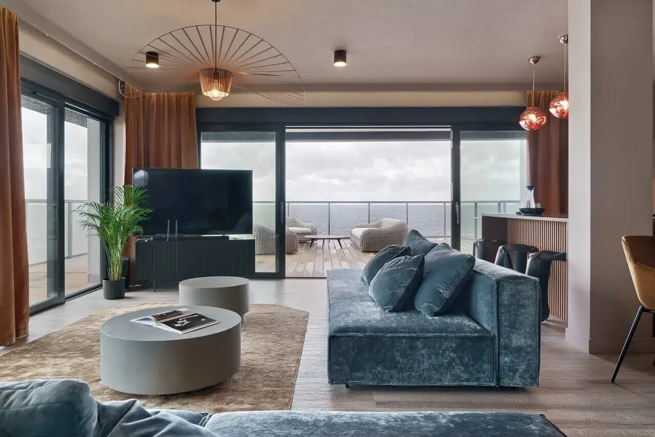Luksusowe penthousy oferują widok na morze z tarasu. Wnętrze zdobi błękitna sofa, okrągłe stoliki i designerska lampa.
