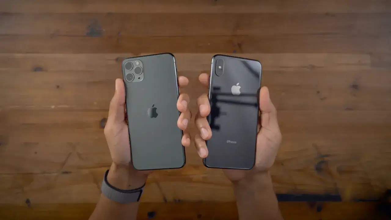 Tv&aring; iPhones h&aring;lls upp mot en tr&auml;bakgrund. Den ena &auml;r m&ouml;rkgr&aring; med tre kameror, den andra &auml;r svart med en kamera. Dags att byta iPhone?