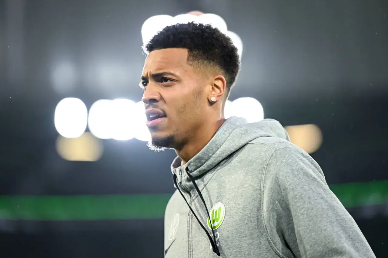 Felix Nmecha, ein Fußballspieler, trägt einen grauen Kapuzenpullover mit dem Wolfsburg-Logo.
