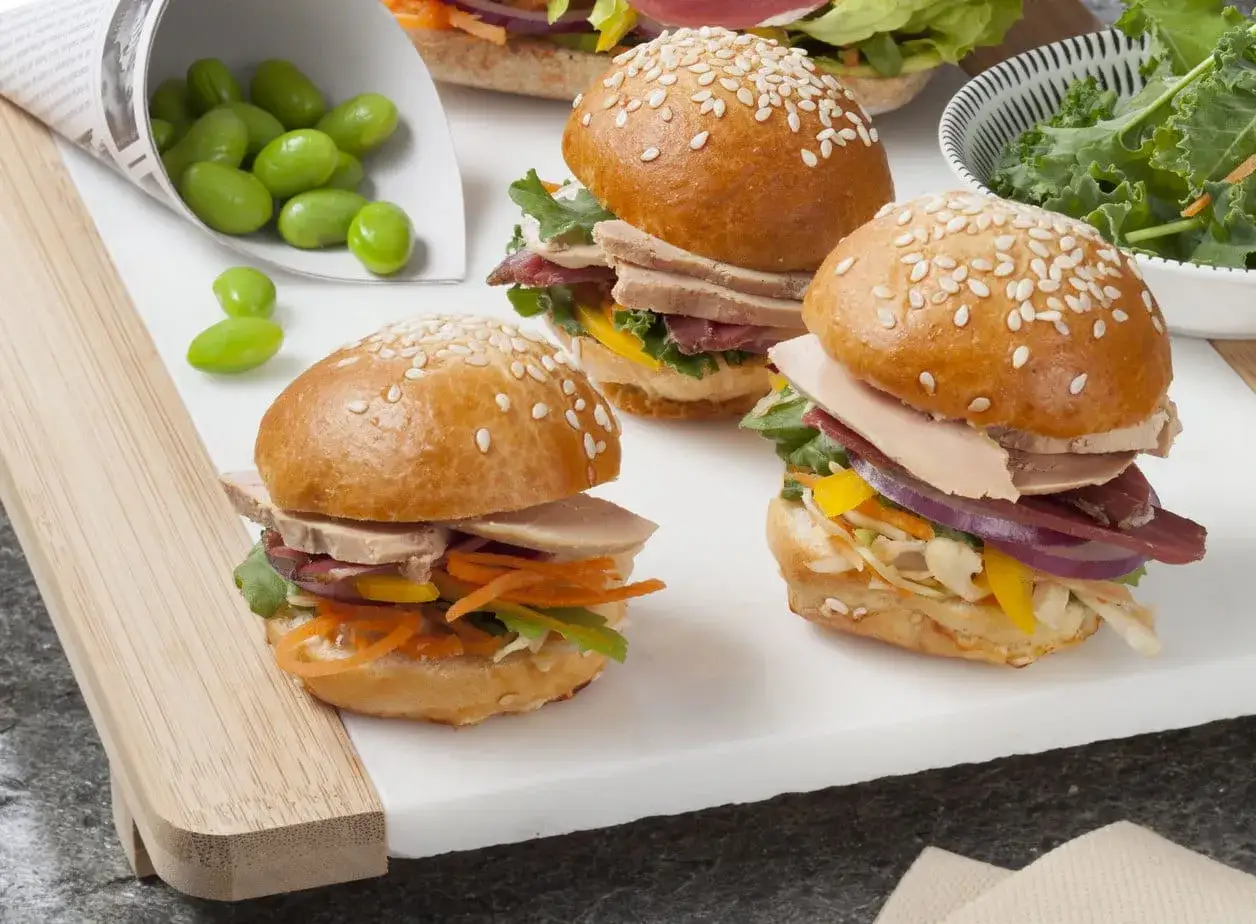 Trois mini burgers de foie gras, garniture color&eacute;e, edamame et salade verte.