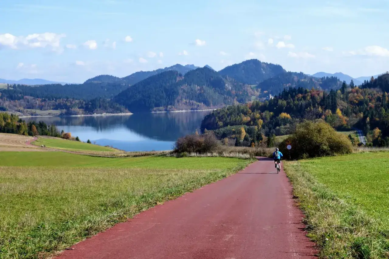 Rowerzysta na czerwonej ścieżce rowerowej. Piękna velo dunajec trasa z widokiem na jezioro i góry jesienią.