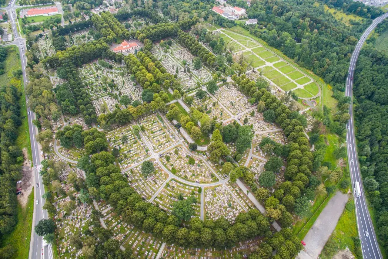 Widok z lotu ptaka na cmentarz centralny w Gliwicach, z alejkami i nagrobkami otoczonymi zielenią.
