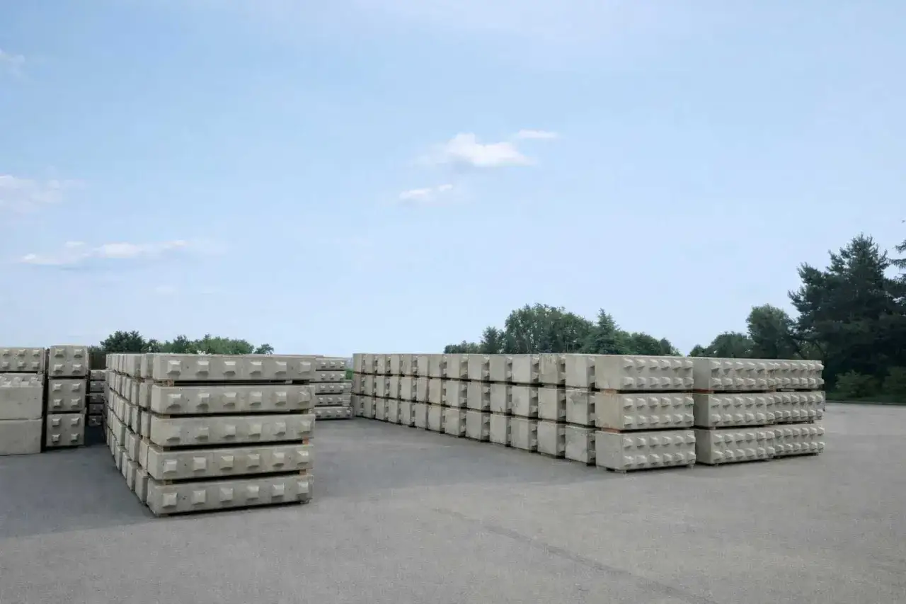 Stosy betonowych elementów z wypustkami, gotowych do budowy. Wytrzymały beton C30/37 czeka na swoje zastosowanie.