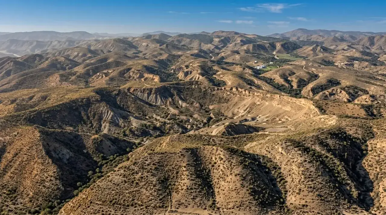 Paisaje árido y montañoso de la sierra de Cabo de Gata, con barrancos y vegetación escasa bajo un cielo azul.