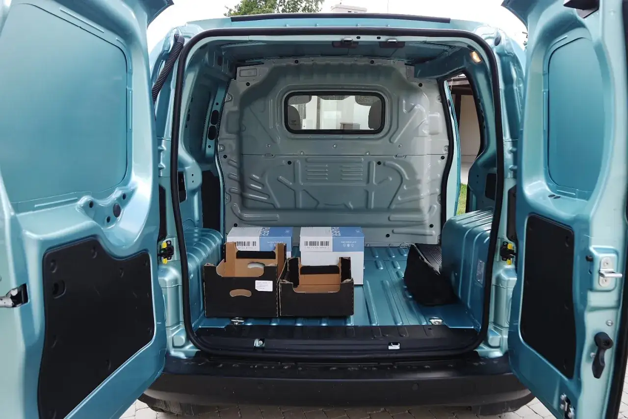 Wnętrze Fiata Fiorino z otwartymi drzwiami. Widać puste pudła i torbę. Idealne do transportu, poznaj fiat fiorino wymiary paki.