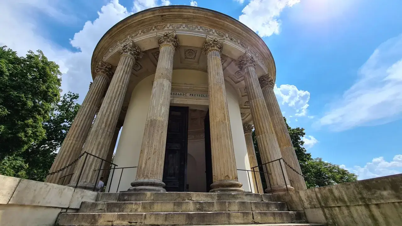 Świątynia Sybilli w Puławach, miejsce pełne historii i ciekawostek o Izabeli Czartoryskiej. Monumentalne kolumny i błękitne niebo.