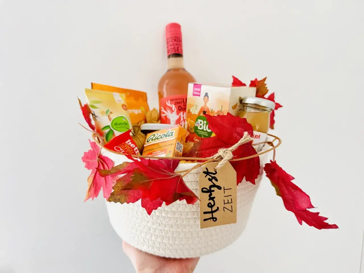 Ein liebevoll zusammengestellter Geschenkkorb, perfekt zum selber machen. Mit Wein, Snacks und herbstlichen Blättern dekoriert.