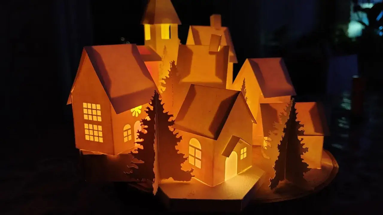 Sagome di un villaggio di Natale da ritagliare, illuminate dall'interno, creano un'atmosfera magica.