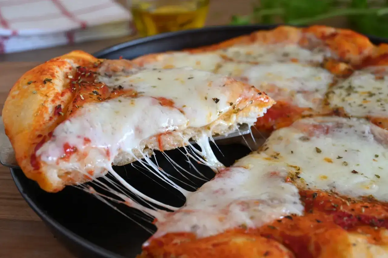 Una fetta di pizza con lievito di birra, filante e dorata, pronta per essere gustata.