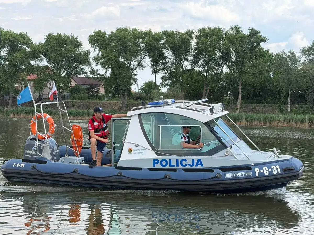 Policjanci na pontonie patrolują wodę, przypominając o przepisach dotyczących pływania pontonem.