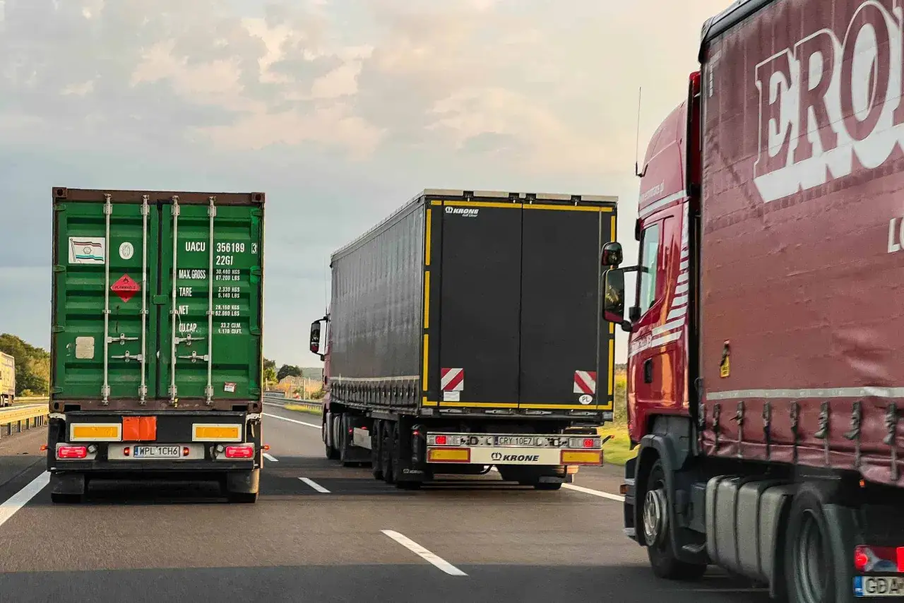 Trzy ciężar&oacute;wki jadące autostradą. Znak 